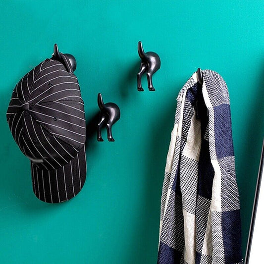 black dog tail wall hooks on green wall 